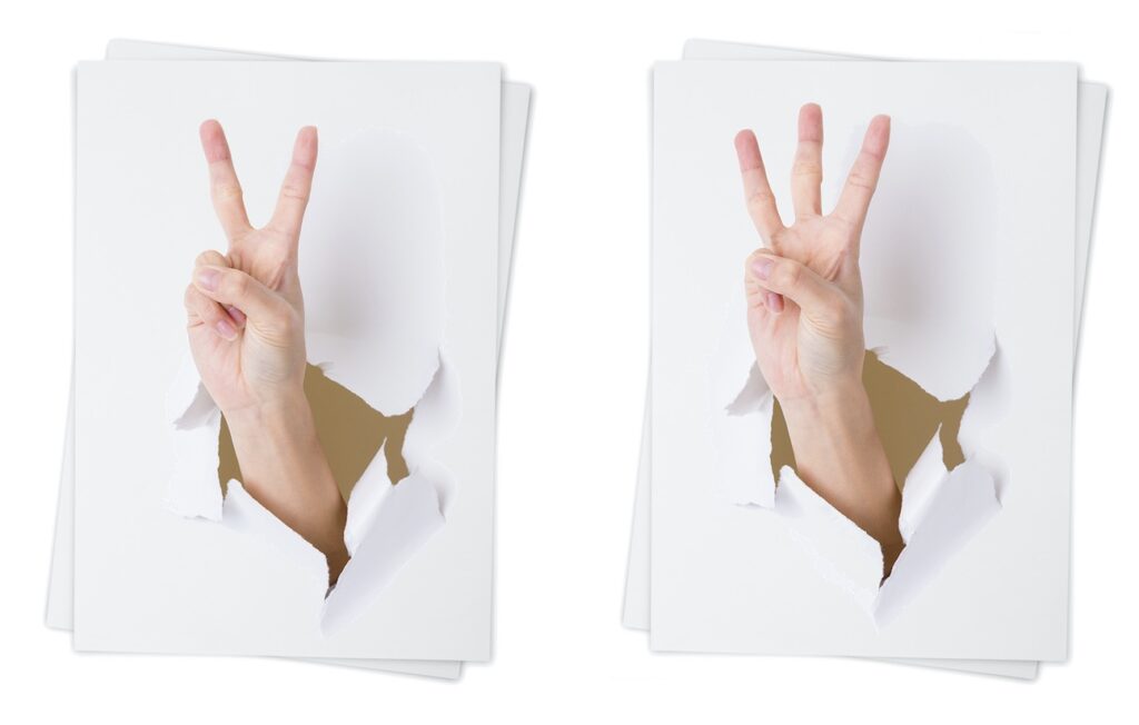 2 and 3 fingers bursting through white paper