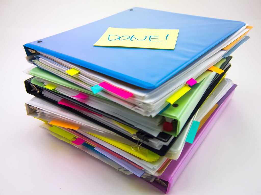photo of pile of documents with a sticky note saying DONE