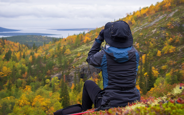 woman looking at a valley through binoculars