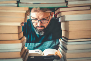 man seen through hole in pile of books