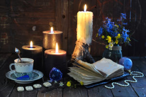 Candles, teacup and open book on table