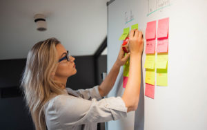 woman moving sticky notes around a board to manage a project