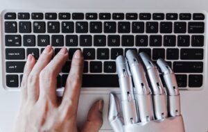 one human hand and one robot hand on keyboard