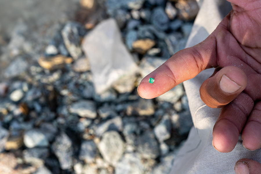 A tiny piece of emerald on a miner's fingertip